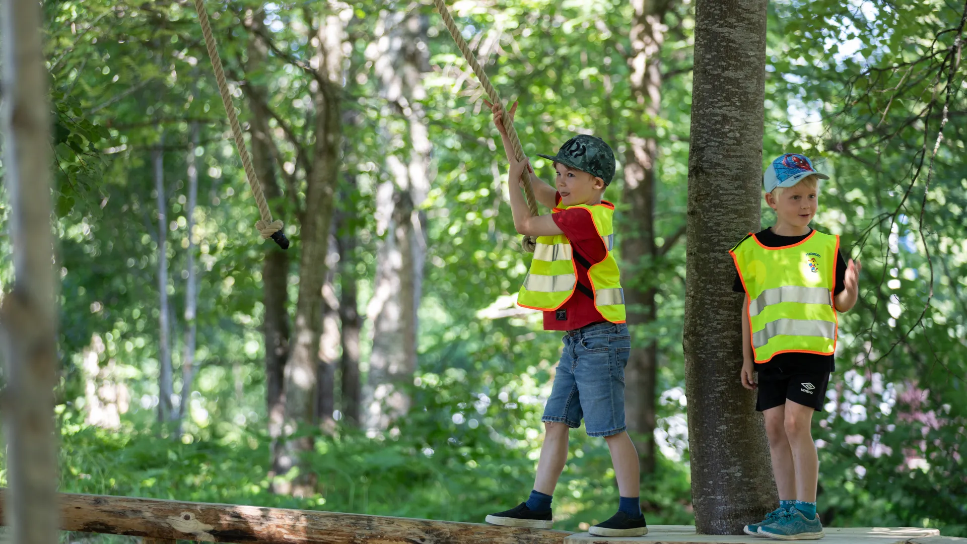 Två unga pojkar som står på en träplattform i skogen.