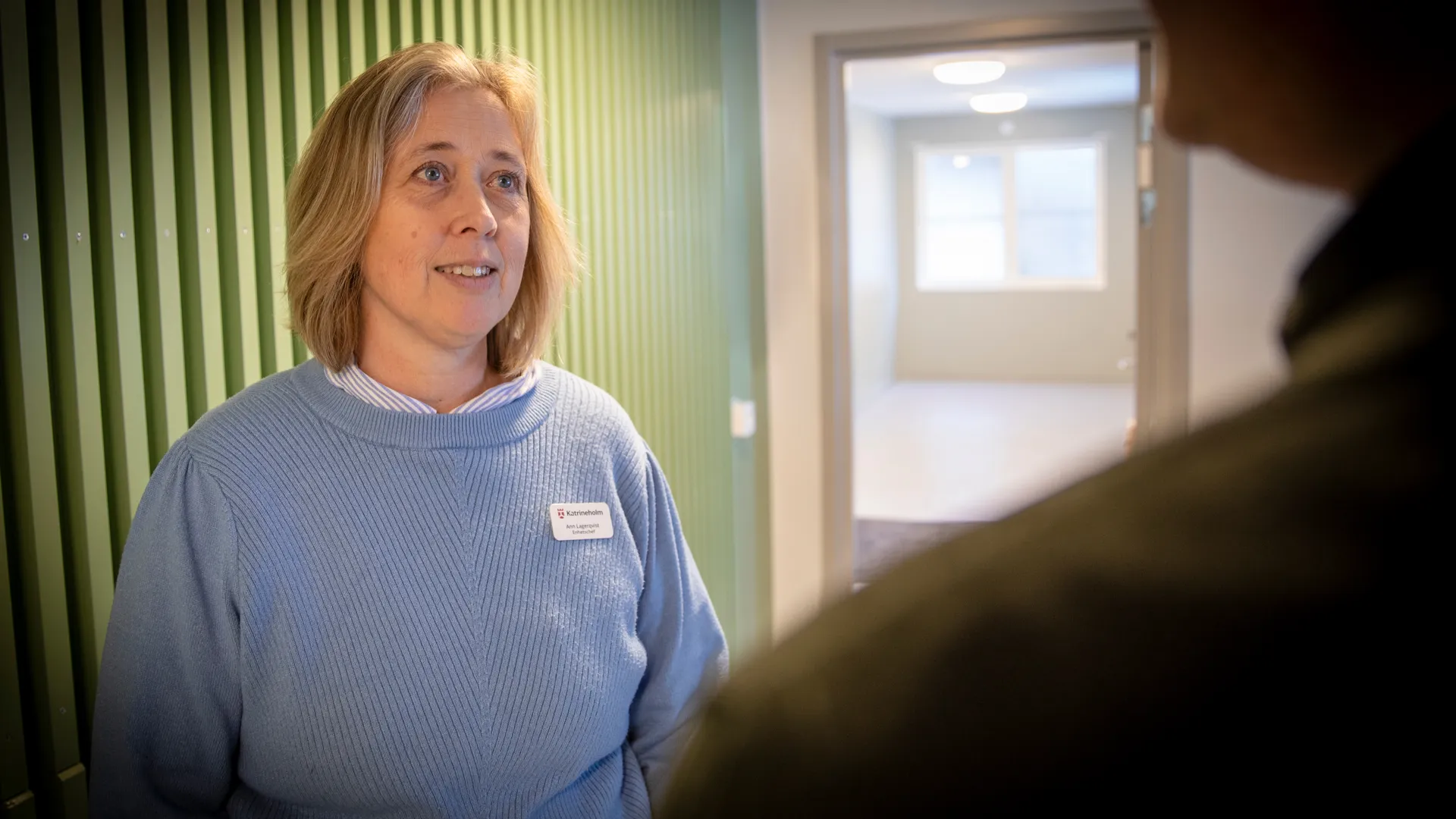 En kvinna med blå tröja har en konversation med en man.