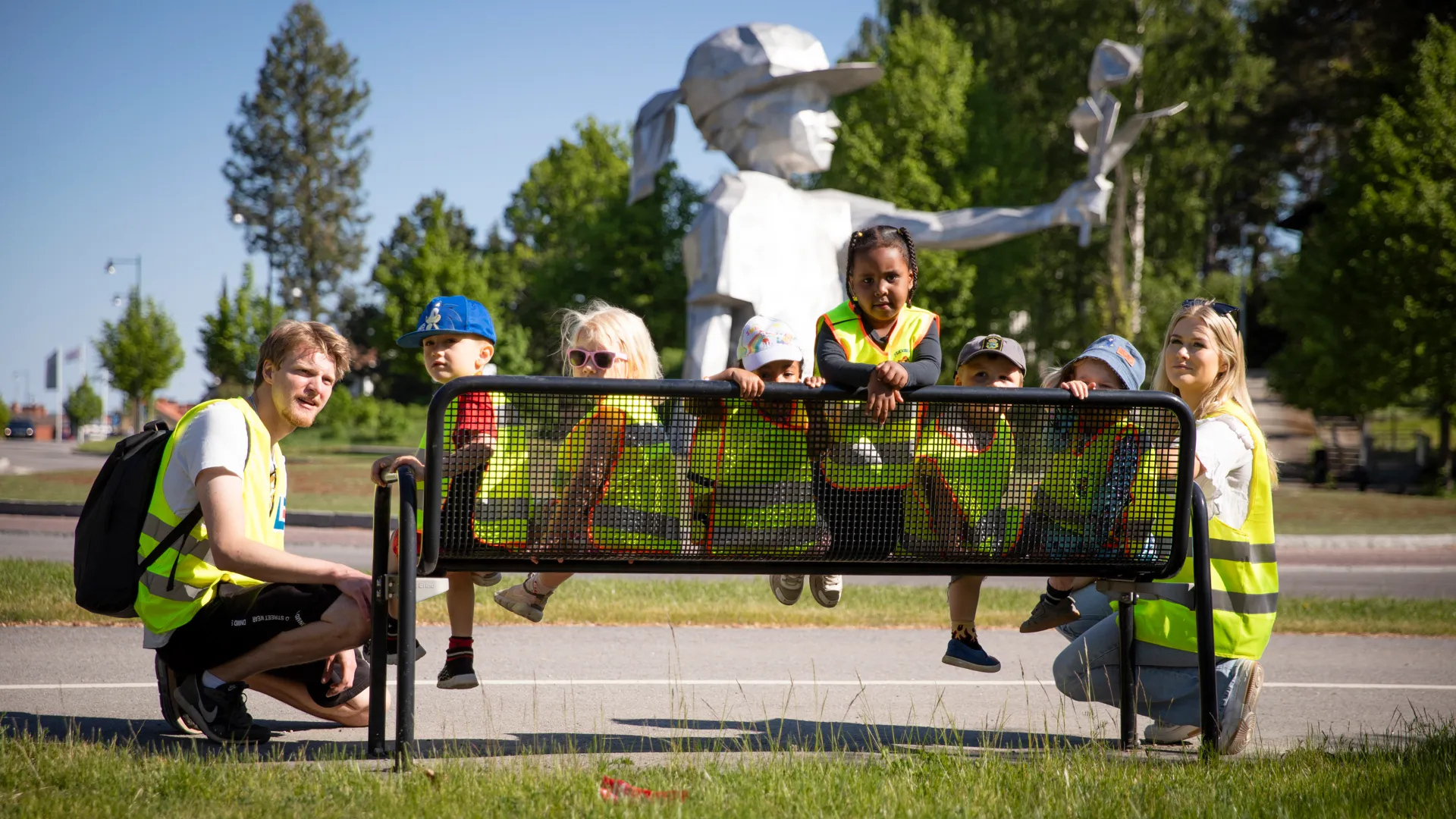 En grupp människor som sitter på en bänk framför en staty.