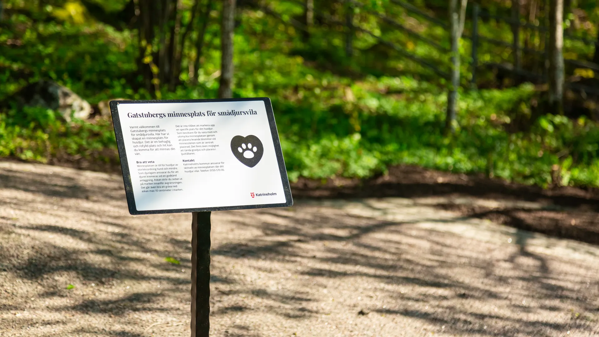 En skylt mitt i en skog med träd i bakgrunden.