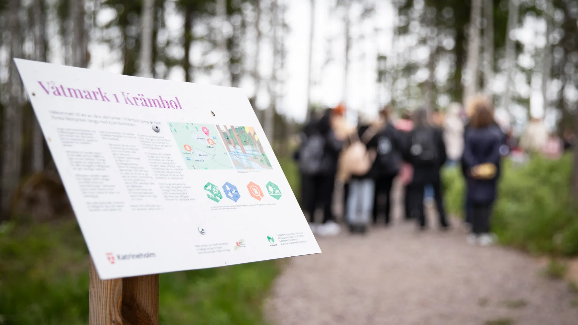 En grupp människor som står runt en skylt.