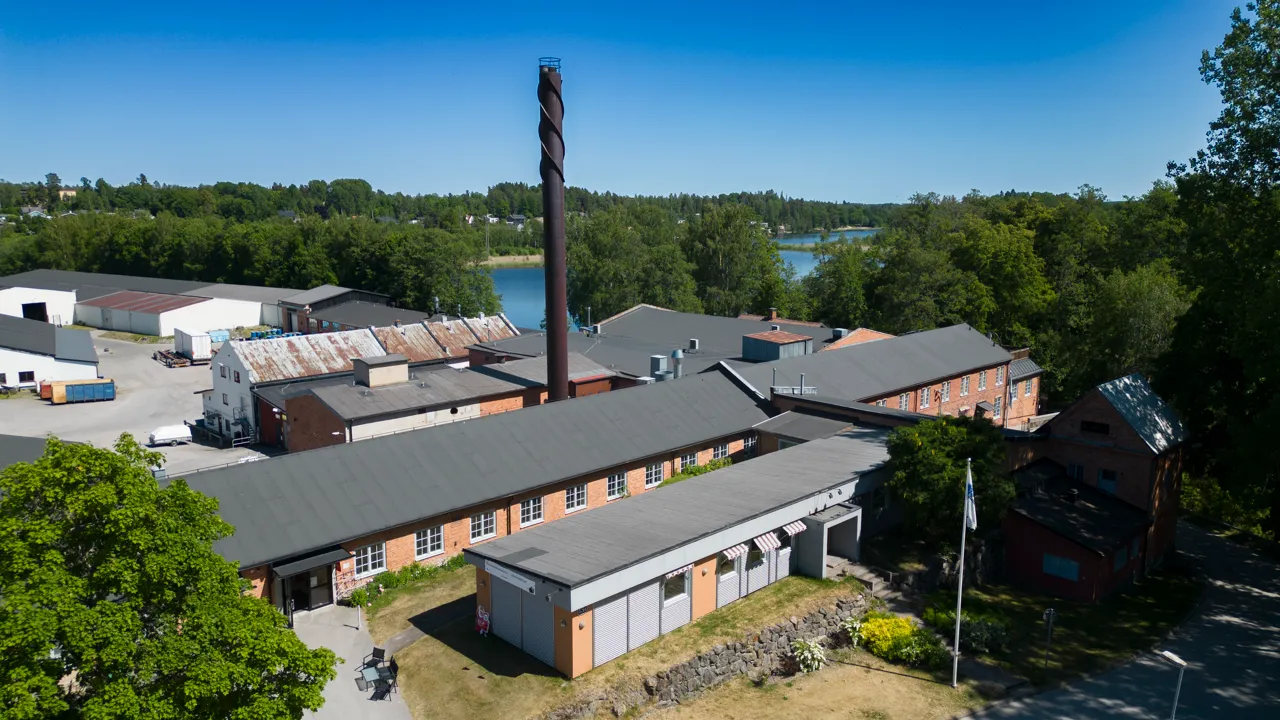 En flygbild av en röd tegelbyggnad, med en sjö i bakgrunden.