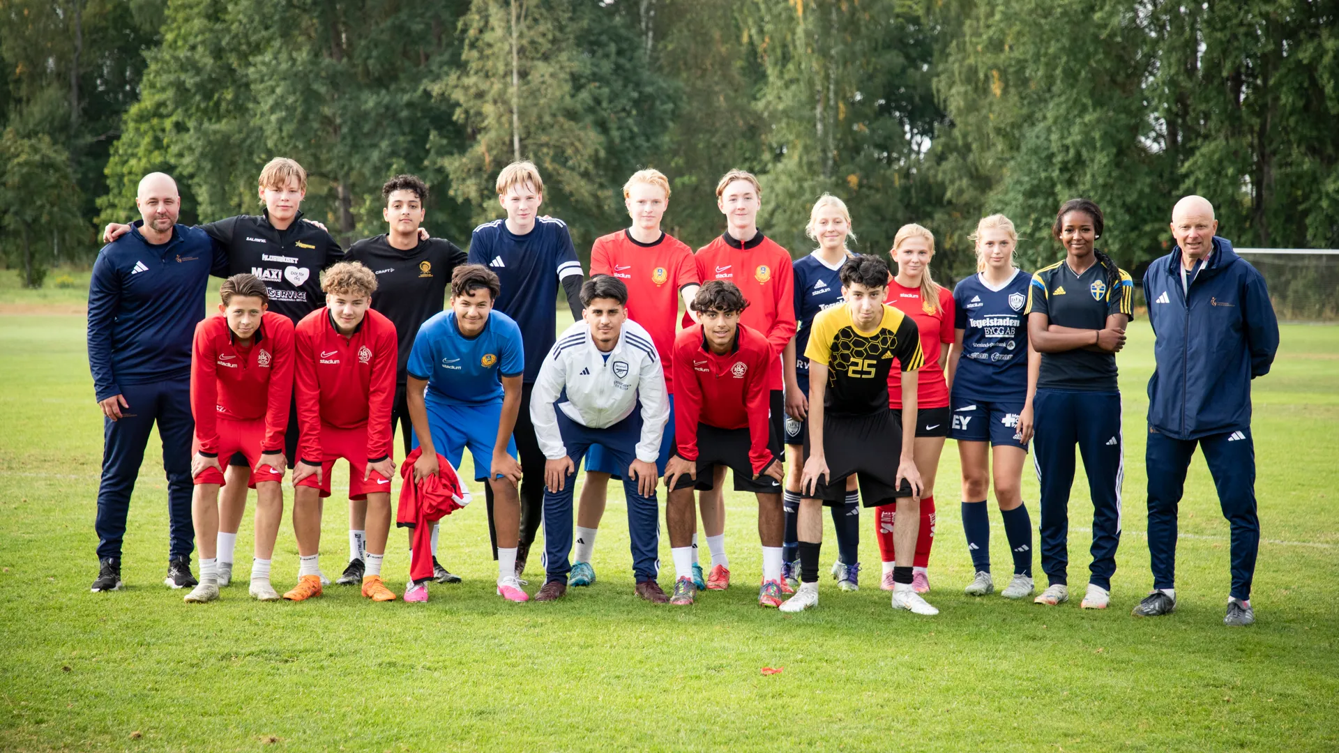 En grupp människor som står bredvid varandra på en äng.