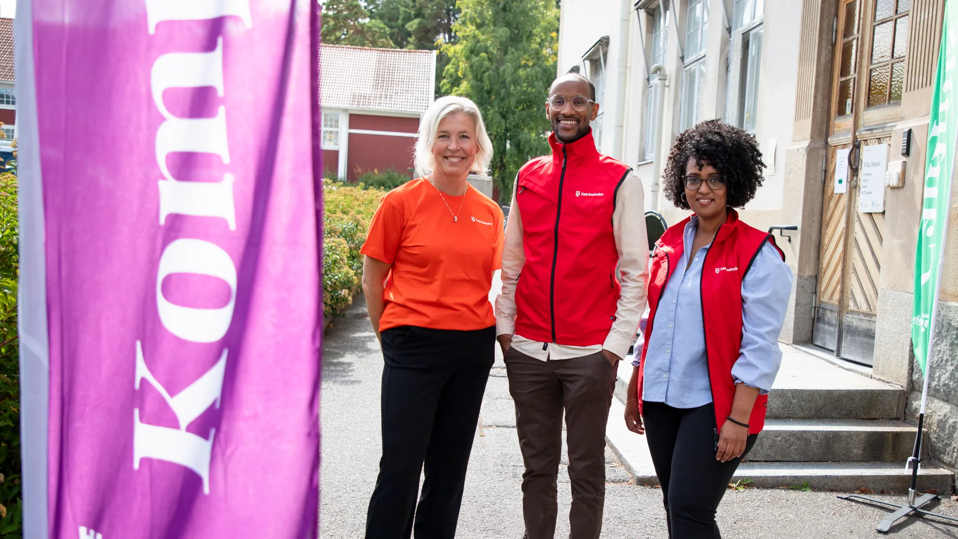 En grupp människor som står bredvid en lila flagga.