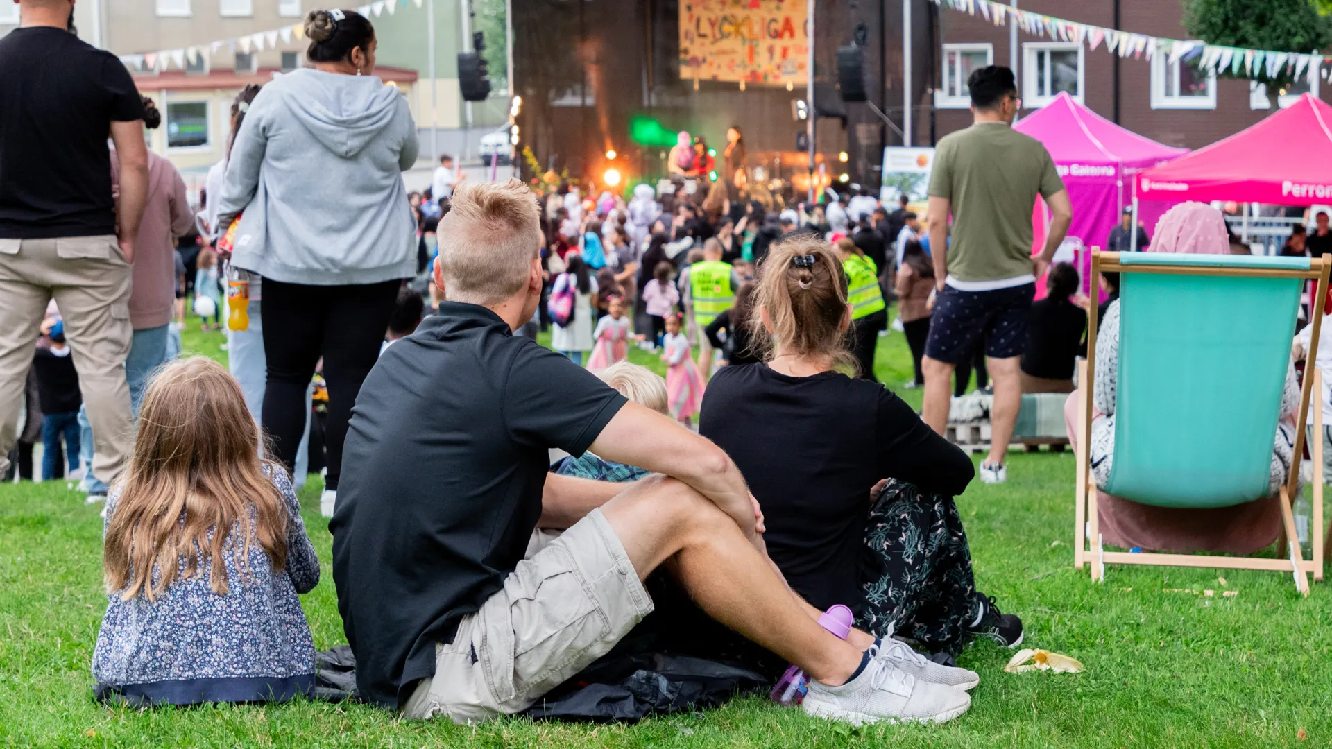 En grupp människor som sitter mitt på en frodig grön äng.