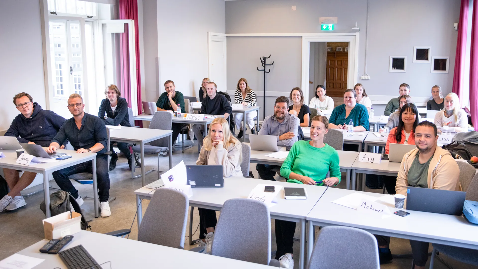 En grupp människor som sitter vid skrivbord i ett rum.