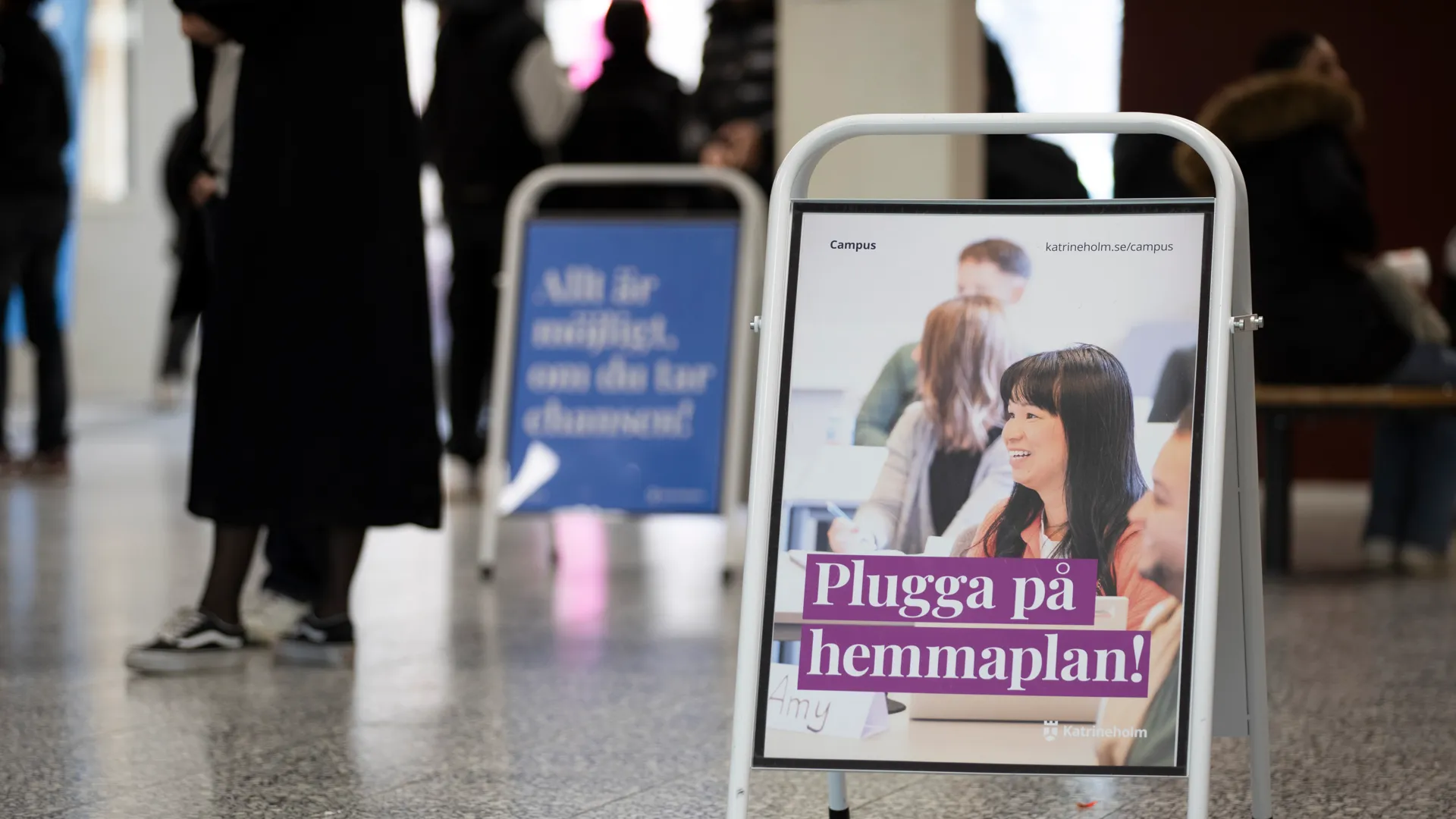 En skylt mitt i en lobby med människor i bakgrunden.