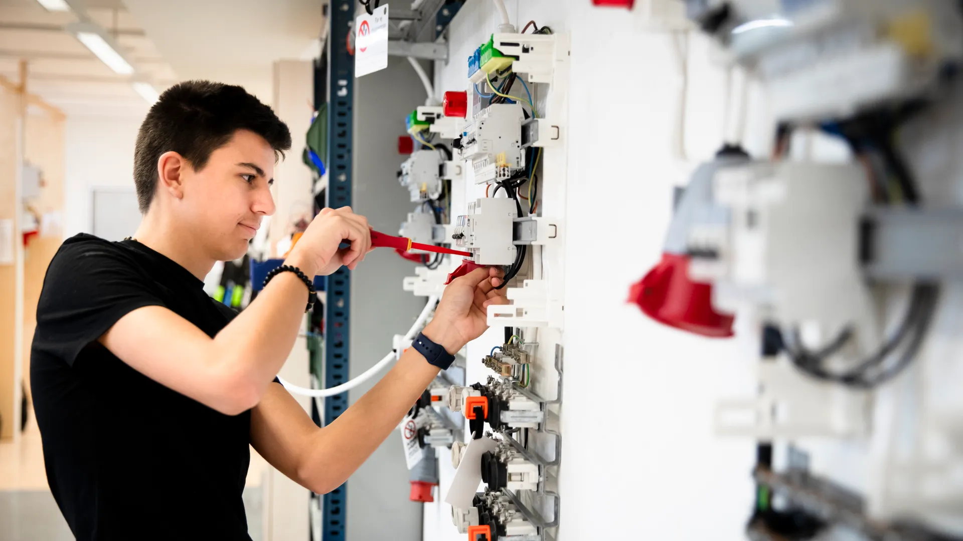 En man som arbetar med elektrisk utrustning i en byggnad.