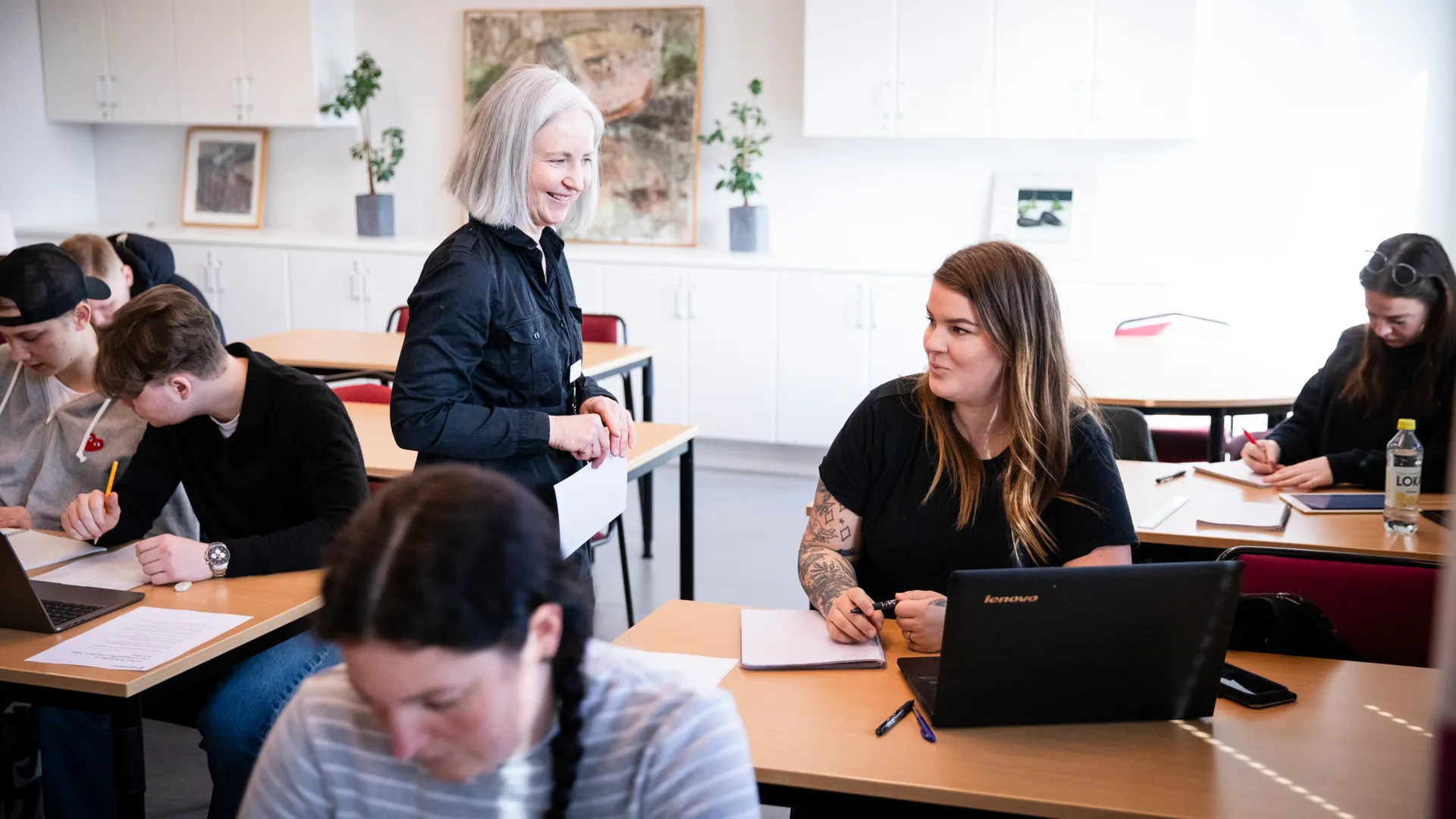En grupp människor som sitter vid skrivbord och arbetar på bärbara datorer.
