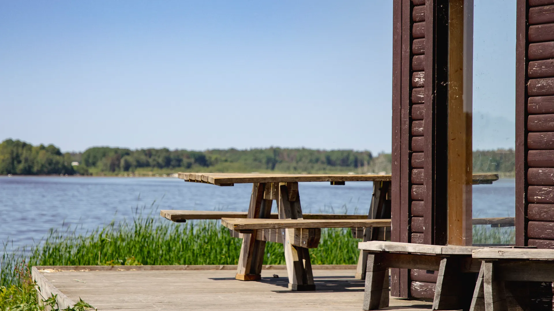 Ett picknickbord står utanför en stuga vid vattnet.