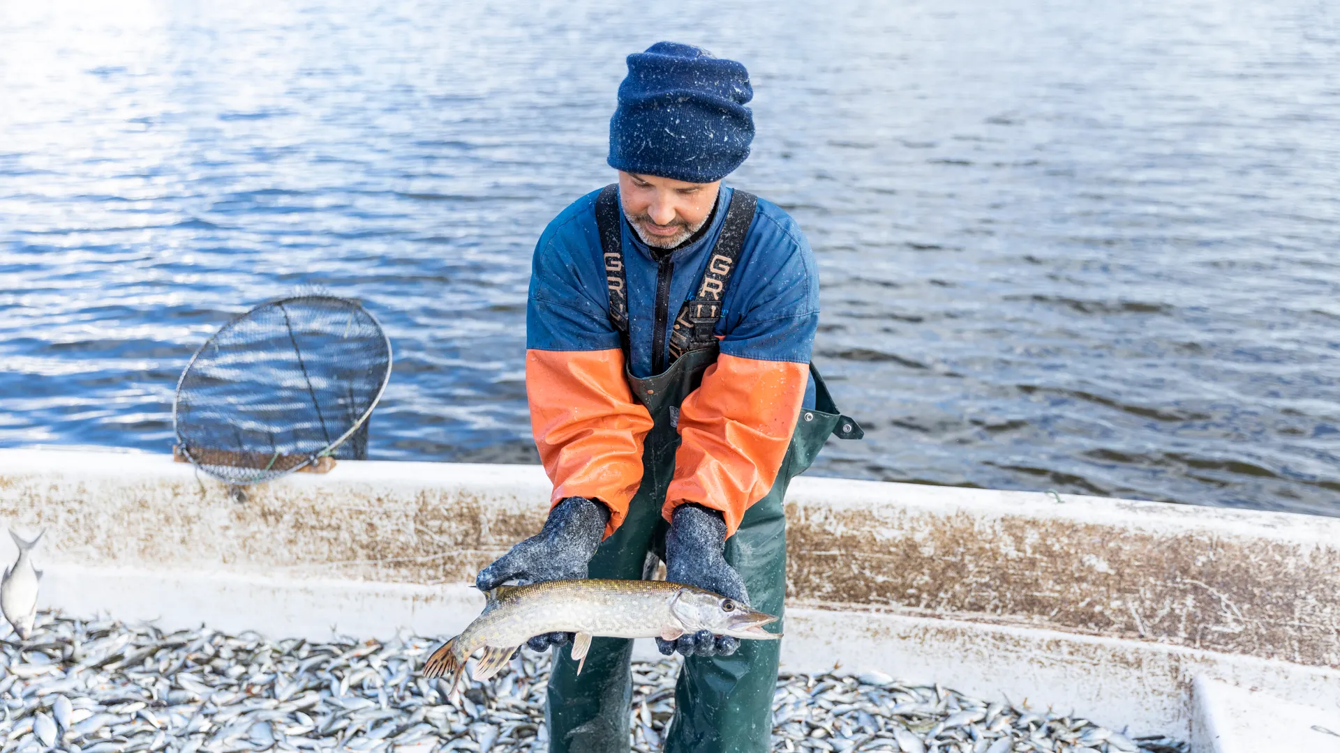 En man som håller en fisk på en båt.