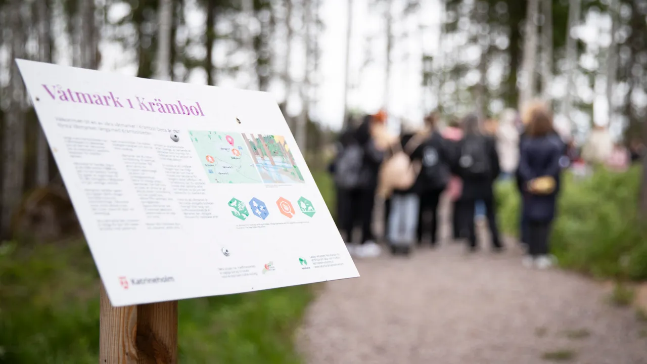 En grupp människor som står runt en skylt.