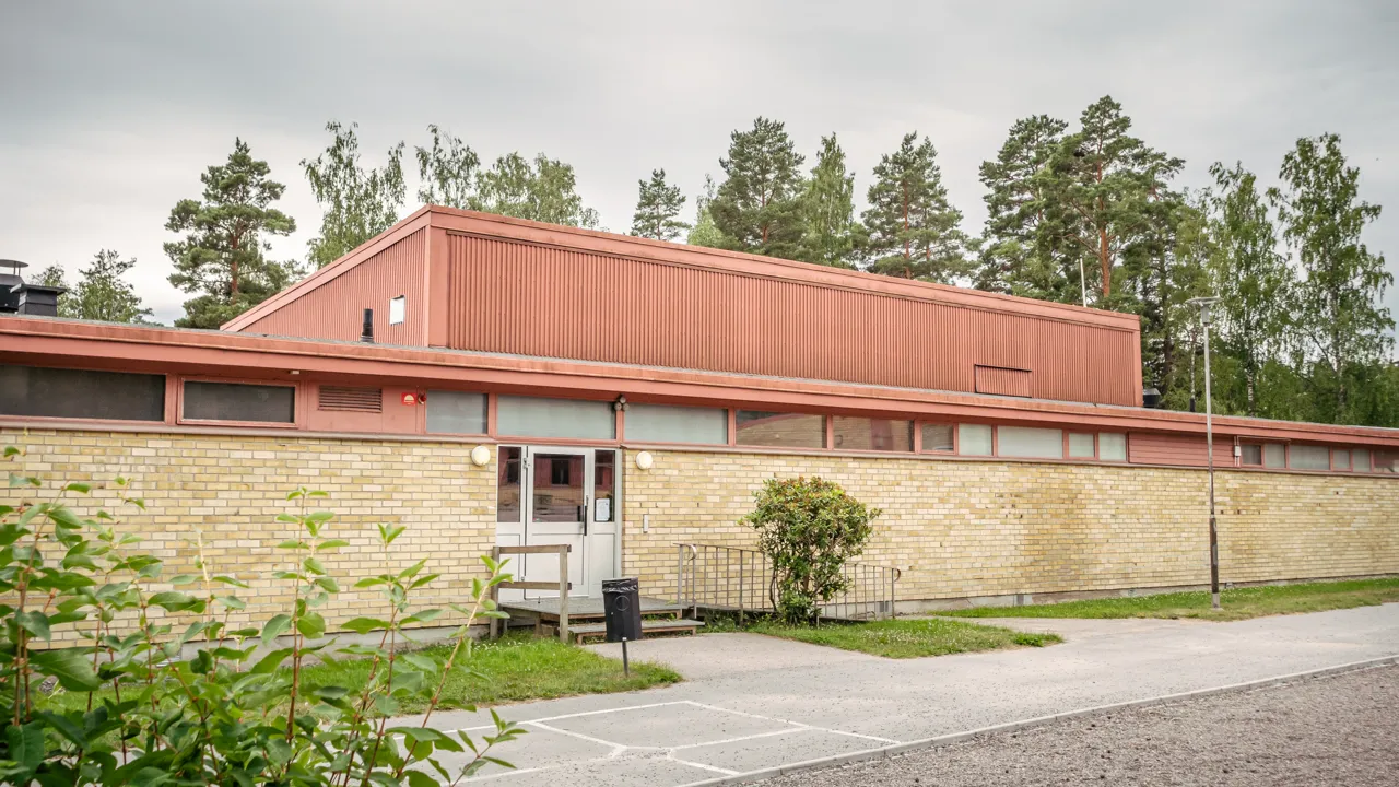En byggnad med rött tak bredvid en parkeringsplats.