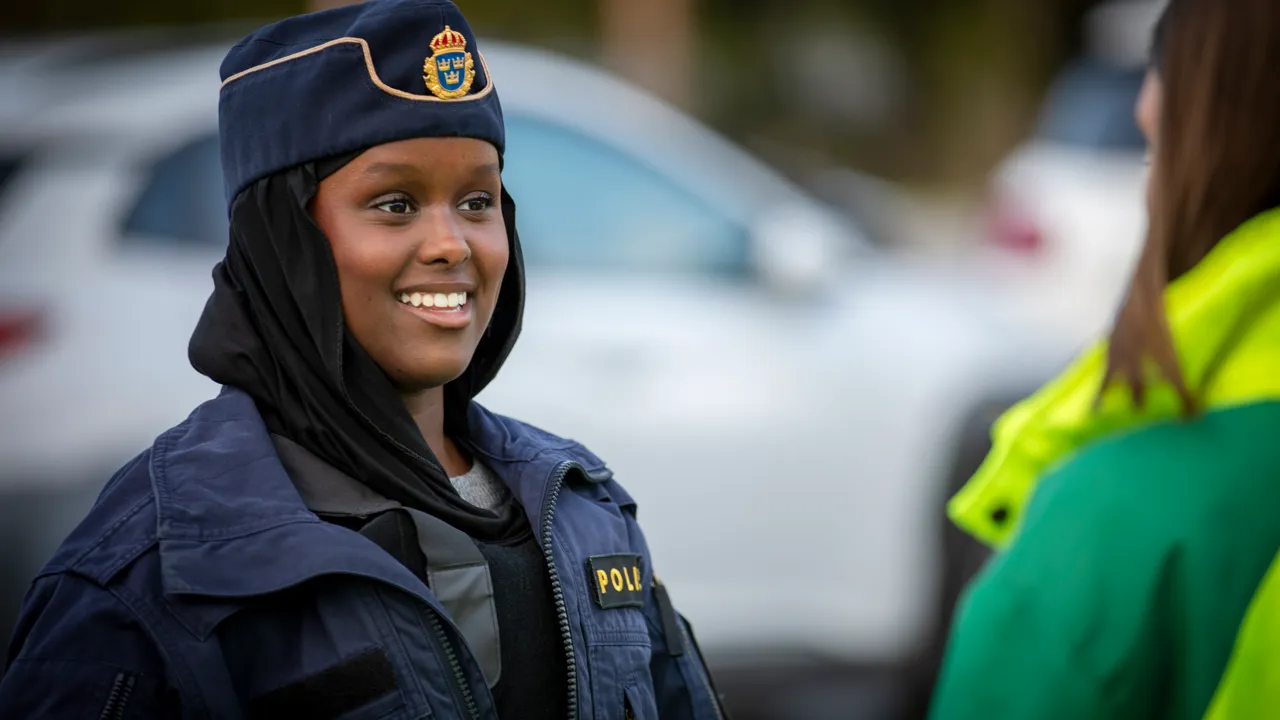 En kvinna i polisuniform som står bredvid en annan kvinna.
