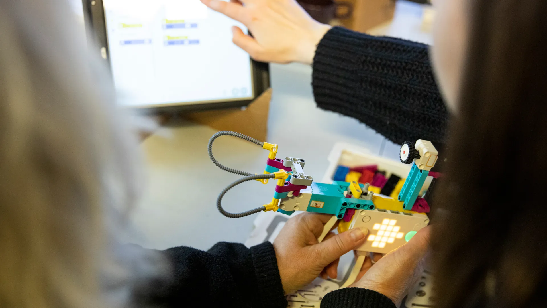 En grupp människor som sitter runt ett bord med legobitar på.
