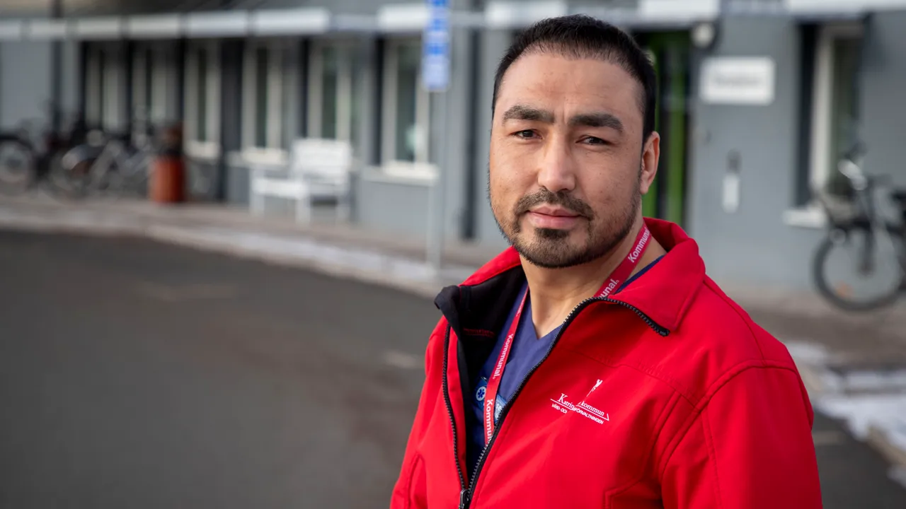 En manlig undersköterska i röd jacka