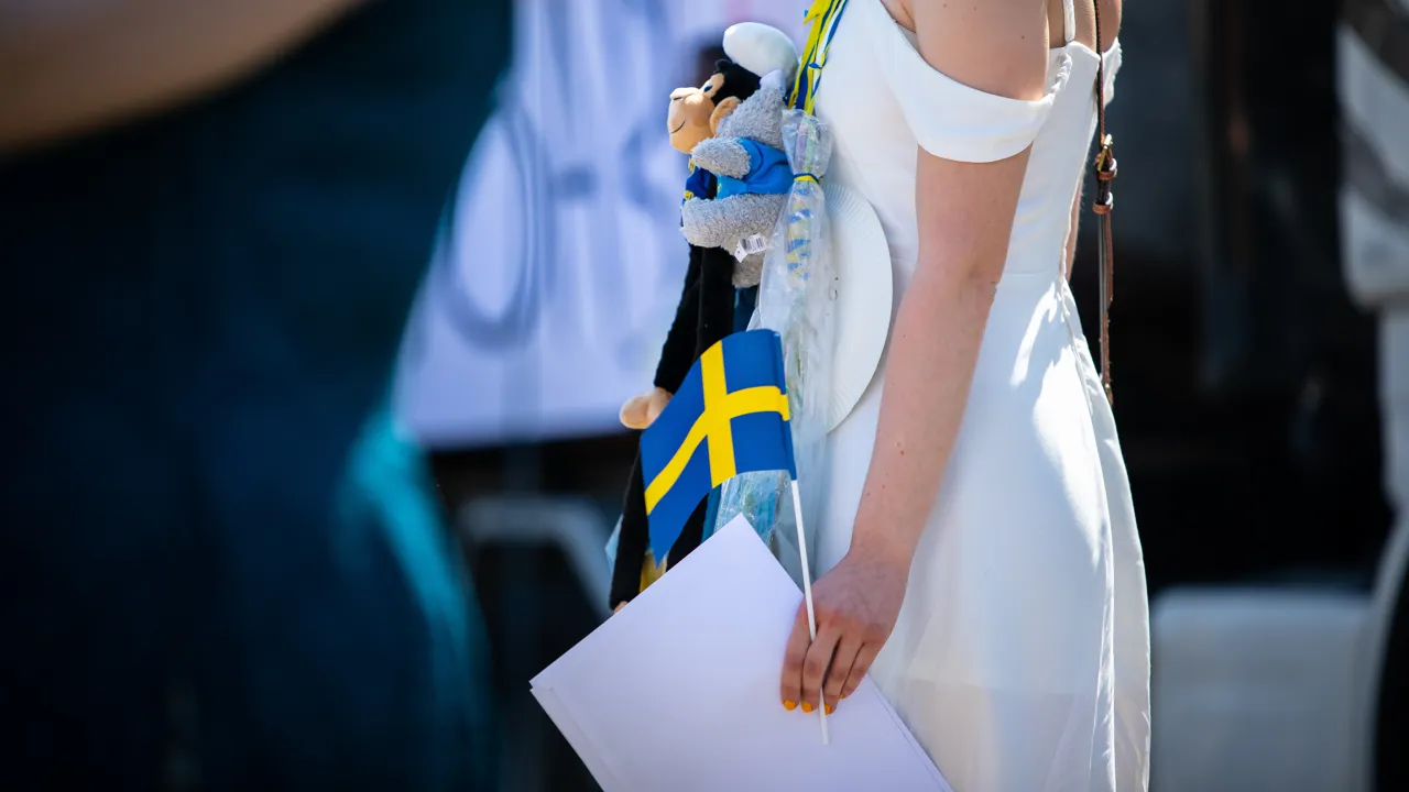 En kvinna i en vit klänning som håller i en flagga.