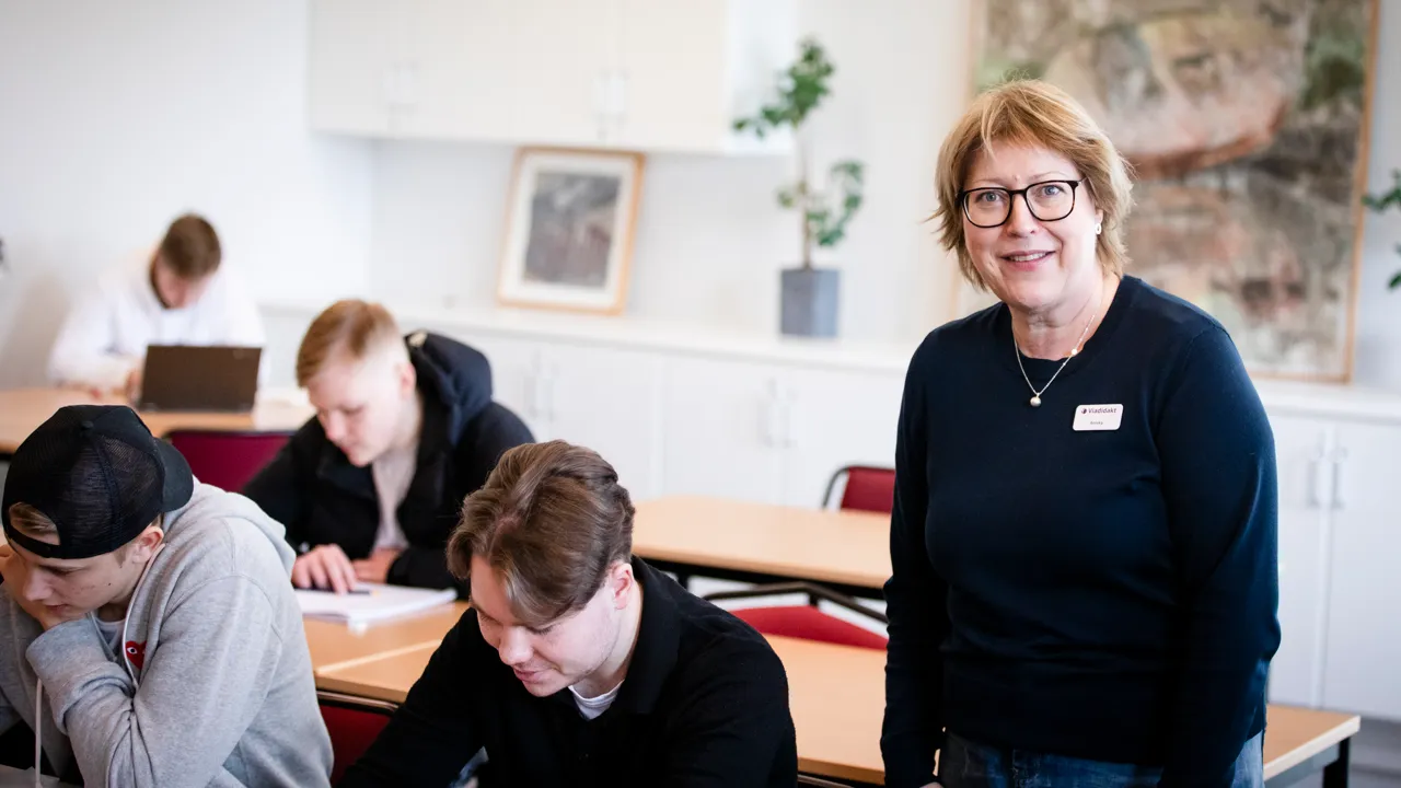 En grupp människor som sitter vid skrivbord i ett klassrum.