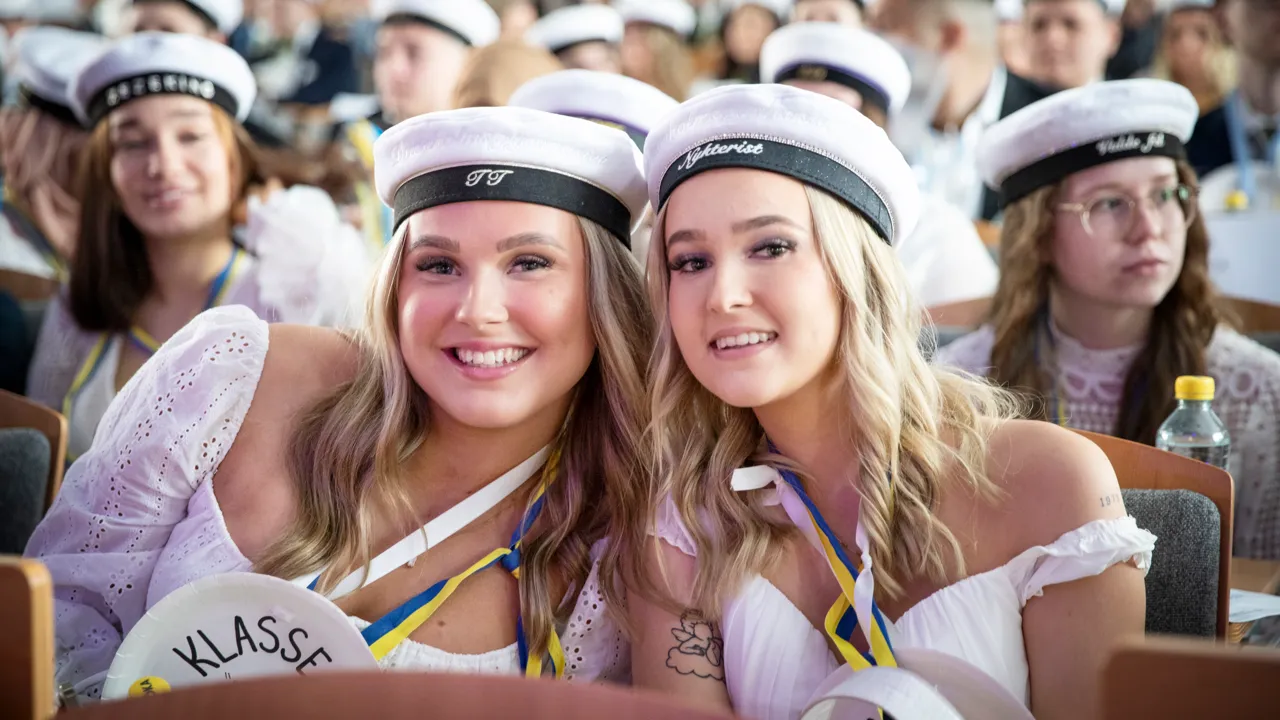 Två kvinnor med studentmössor poserar för en bild.