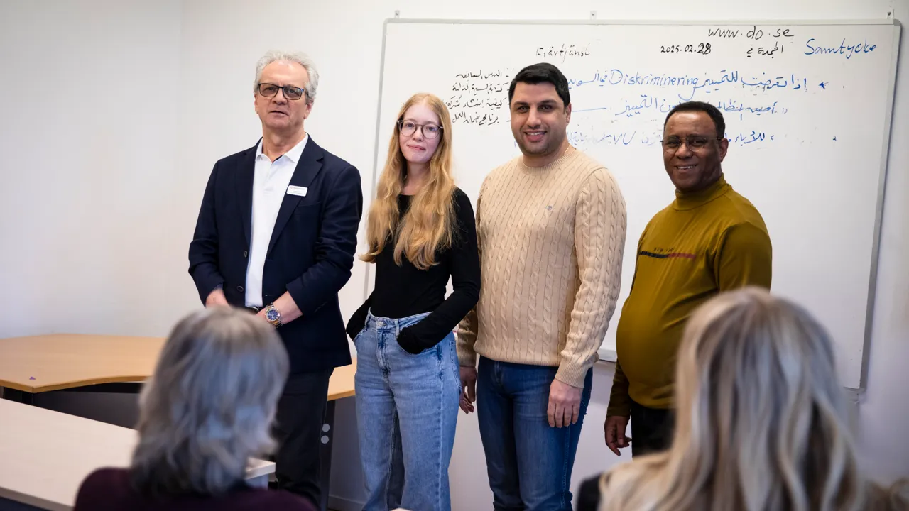 En grupp människor som står framför en whiteboardtavla.