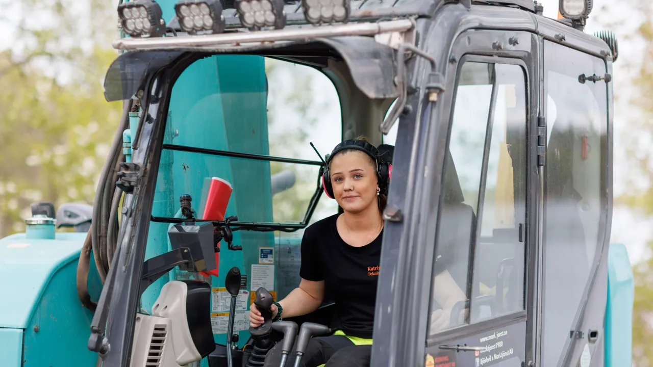 En kvinna som sitter i förarsätet på en traktor.