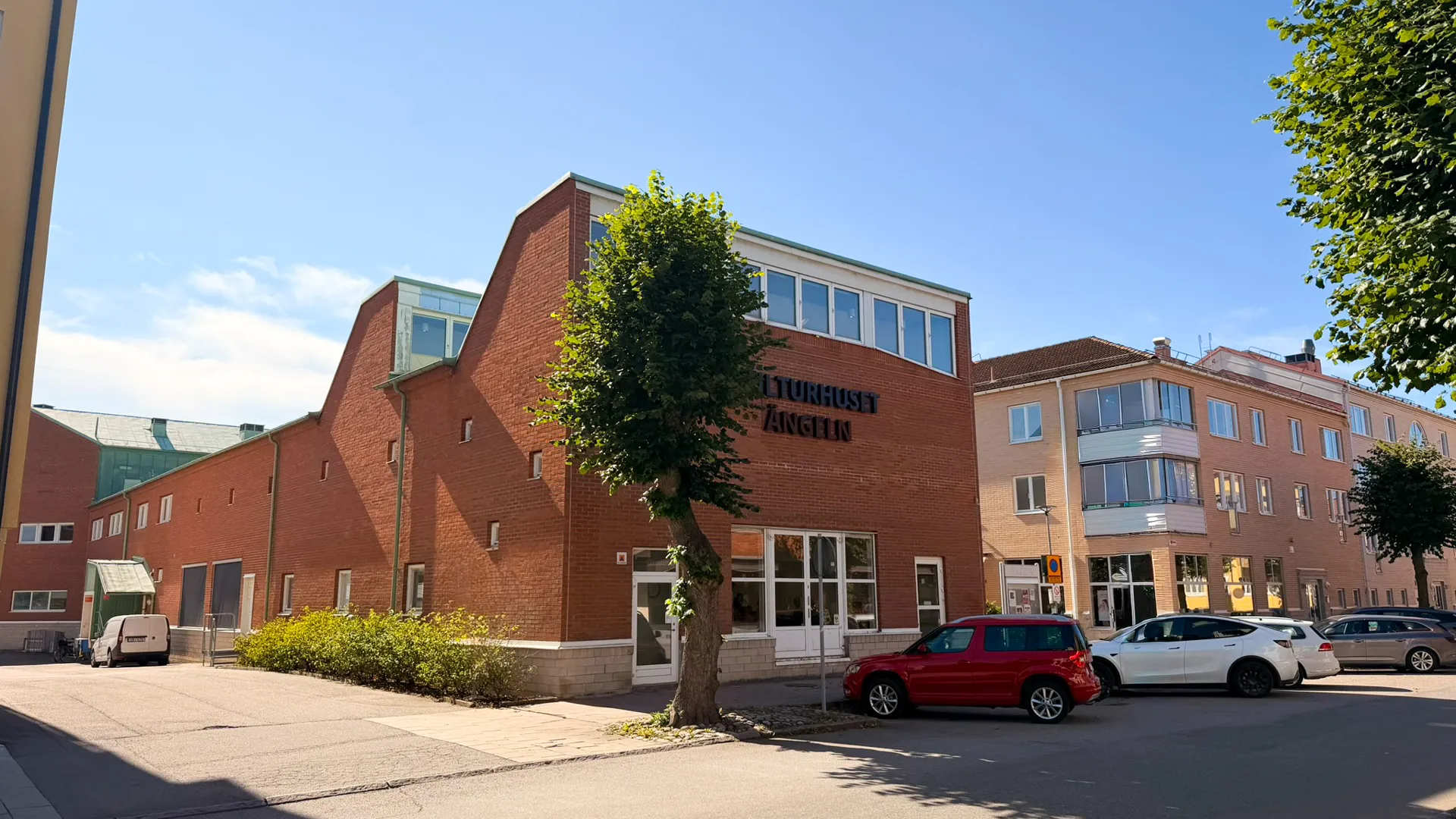 En röd bil som står parkerad framför en byggnad av rött tegel.