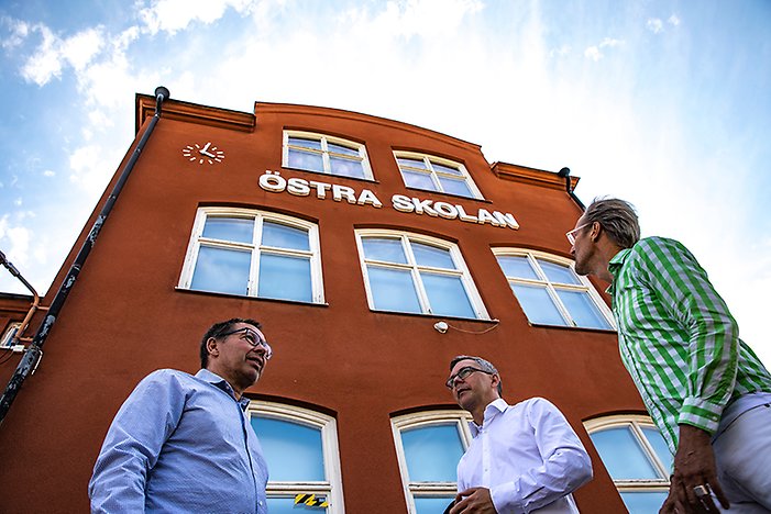Christer Sundqvist (M) kommunstyrelsens vice ordförande, Johan Söderberg (S) kommunstyrelsens ordförande och Magnus Runesson samhällsbyggnadschef framför den pampiga fasaden av Östra skolan.