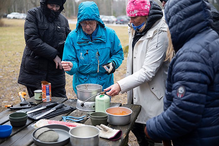 Några personer hjälps åt att få igång spritköket och öppnar konserver med soppan som ska värmas.