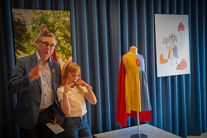 Linnéa Moqvist, 11 år, tillsammans med kommunstyrelsens ordförande Johan Söderberg (S) under invigningen av visionsutställningen där hennes egen visionsklänning är en del av utställningen.