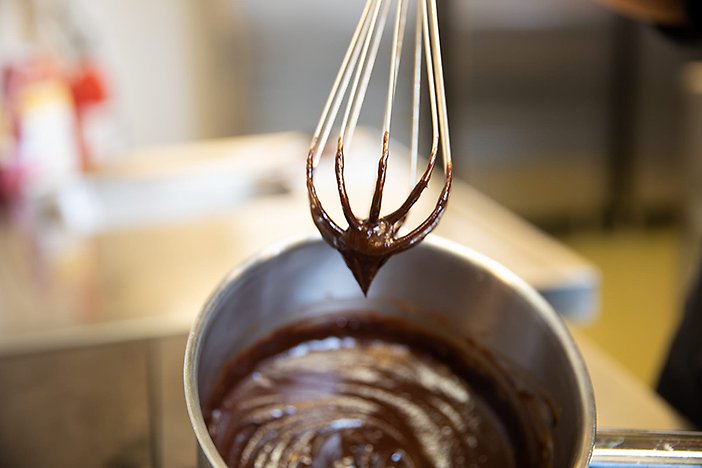 Kastrull med smält choklad och en visp.